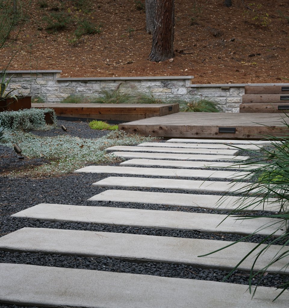 Bastrop Lost-Pines courtyard with paver walkway, limestone walls, and a deck