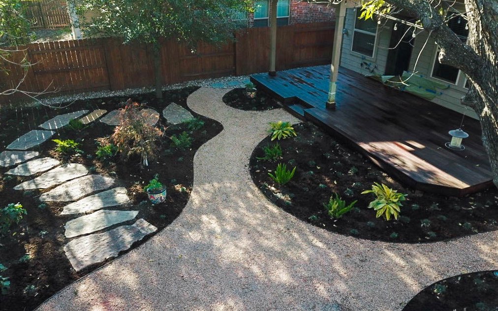 Austin backyard in the River Place neighborhood with a flagstone pathway, decomposed granite, a fire pit, and native planting beds