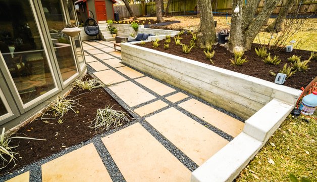 Shoal Creek build combining concrete retaining walls, a flagstone pathway, gravel, and planting beds as part of a full landscape construction