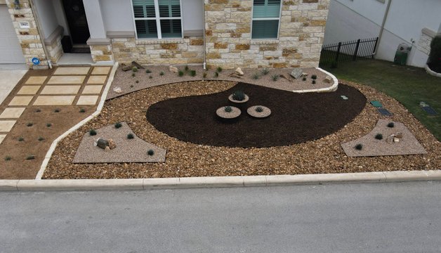 Spicewood front yard xeriscape with gravel, mulch, and planters supported by zoned irrigation