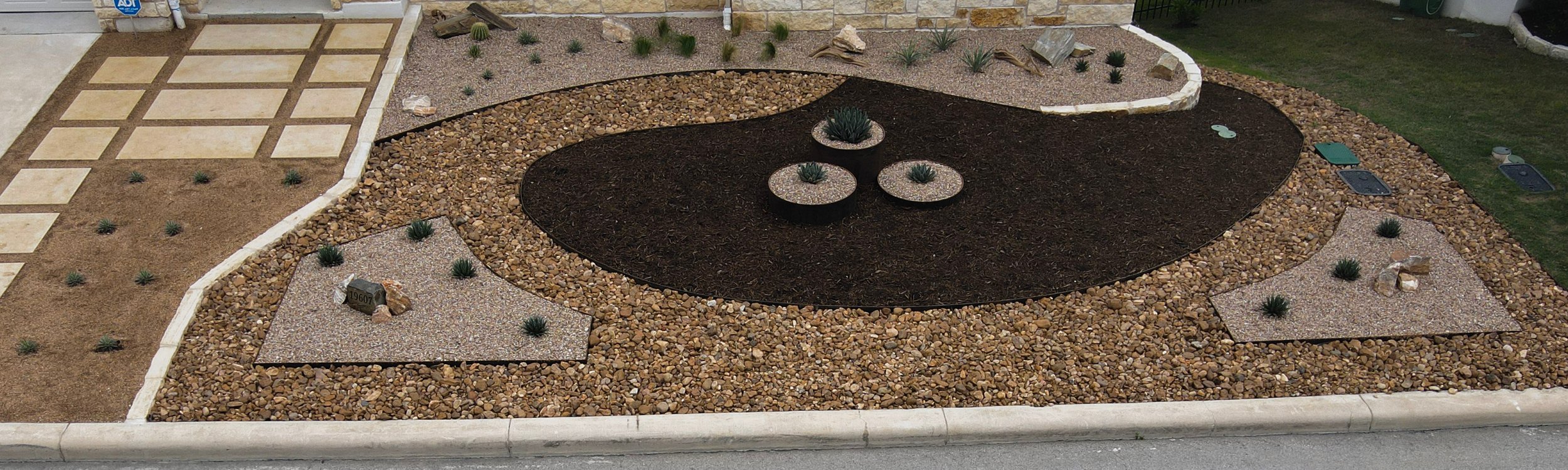Spicewood front xeriscape with gravel, mulch, and planters in a drought-tolerant Austin landscape design