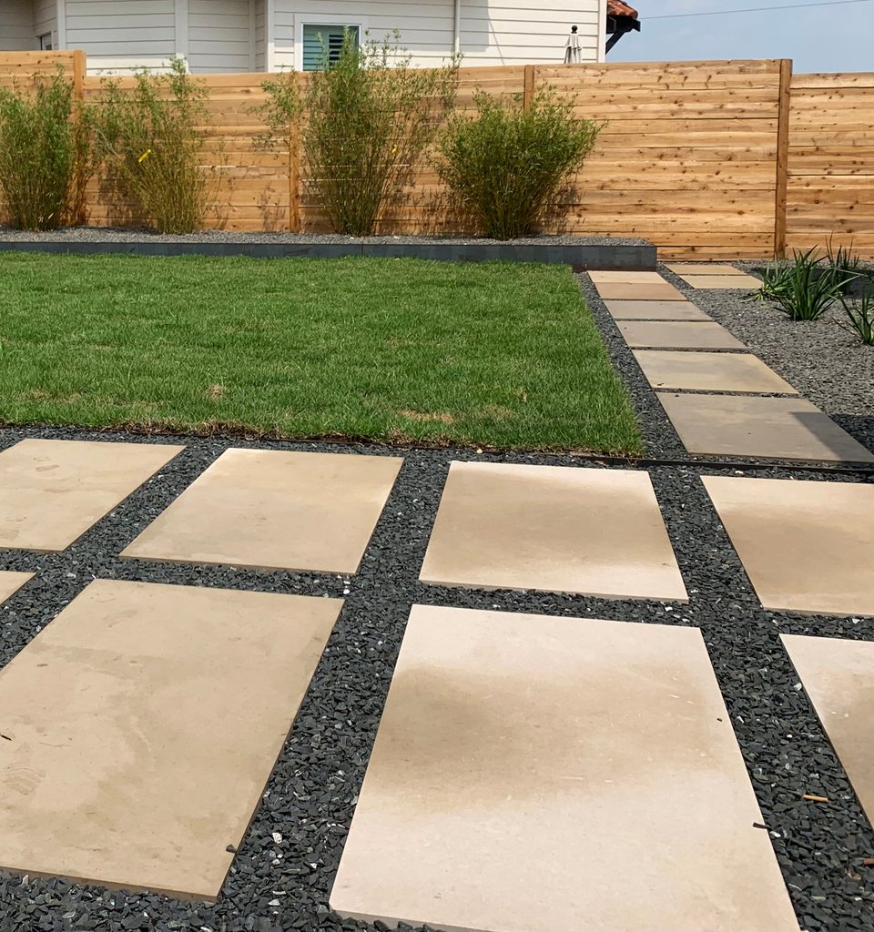 Westlake Hills terrace re-graded with sod, gravel, and planting beds shaping the slope to shed water